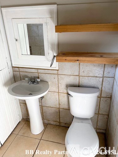 A white toilet sits next to a white pedestal sink in a bathroom.