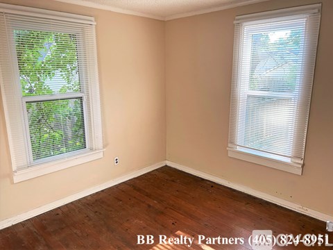 A room with two windows and wooden flooring.