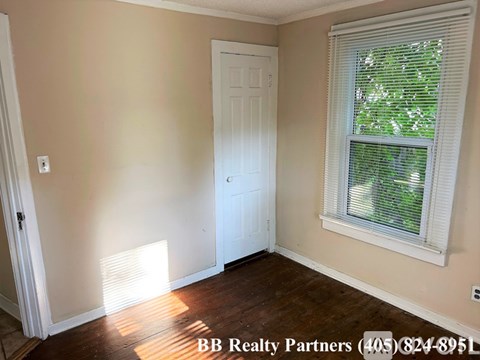 A room with a white door and a window with blinds.