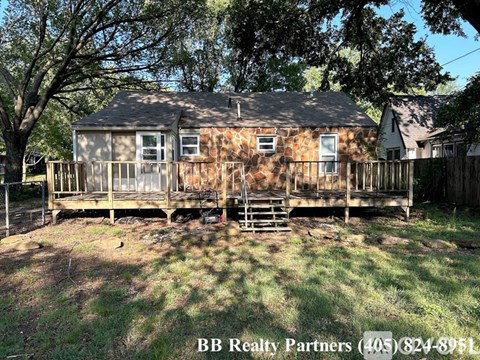 A house with a porch and a tree in front of it.