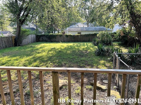 A backyard with a wooden fence and a tree.