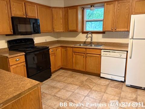 A kitchen with wooden cabinets and a black stove top oven.