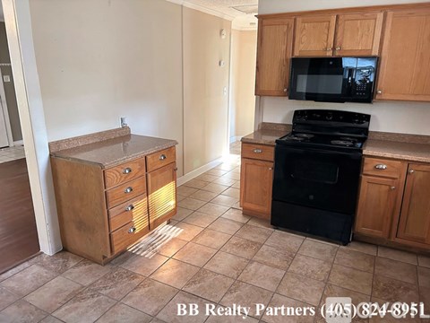 A kitchen with a black stove top oven and wooden cabinets.