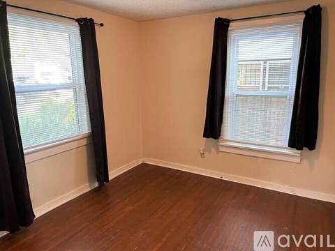 A room with two windows covered by black curtains.