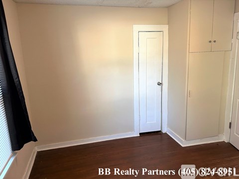 A room with a door, a window with black curtains, and a wall with a cabinet.