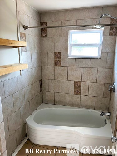 A bathroom with a tub, a window, and a shower.