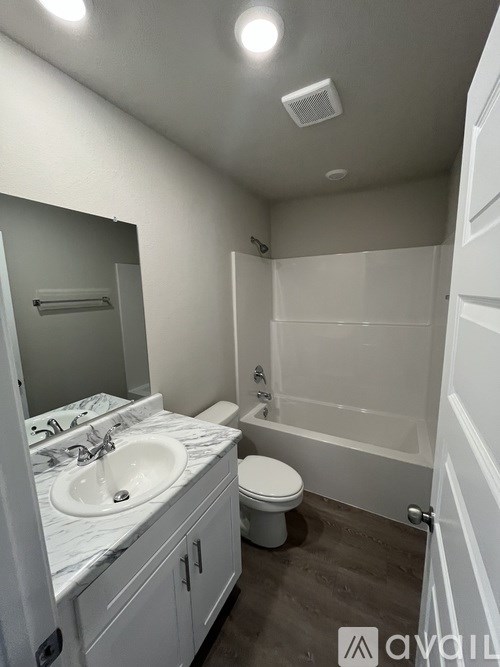 A bathroom with a marble countertop and white fixtures.