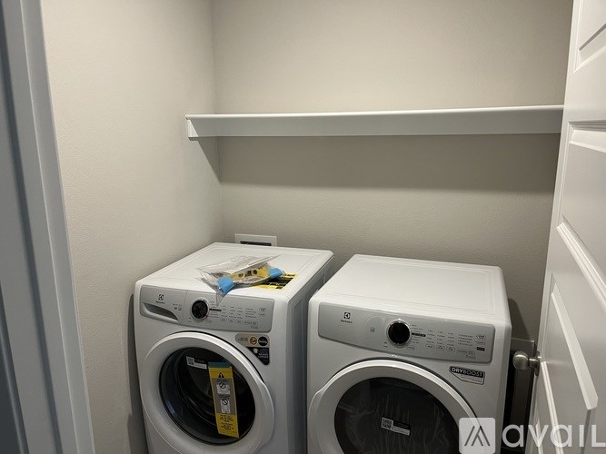Two white front loading washing machines in a small laundry room.
