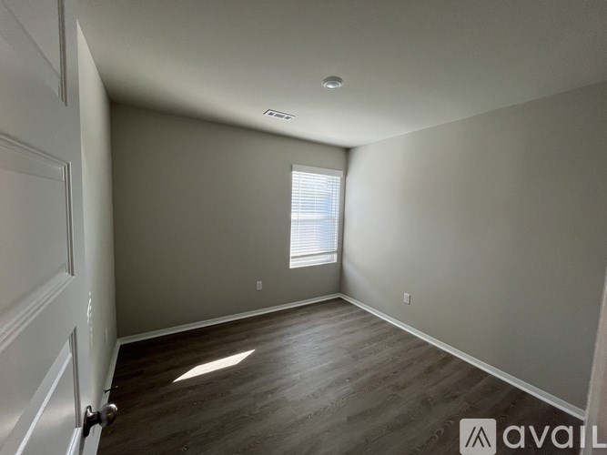 A room with wooden flooring and a window with blinds.