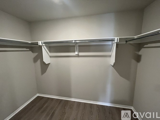 A walk-in closet with a white ceiling and wooden floor.