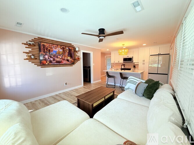 A living room with a white couch and a painting on the wall.