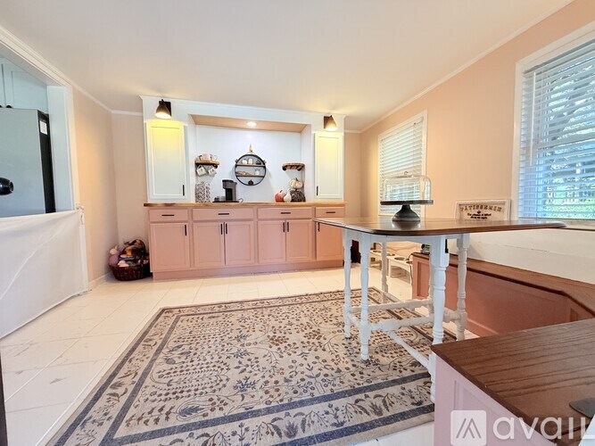 A kitchen with pink cabinets and a rug on the floor.