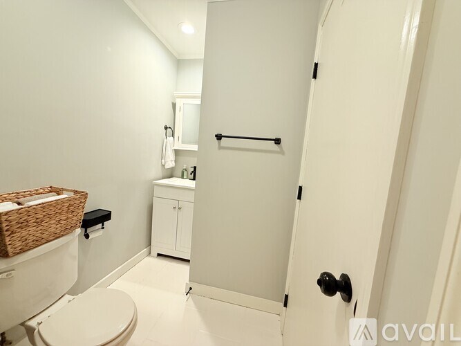 A white bathroom with a toilet, a cabinet, and a towel rack.