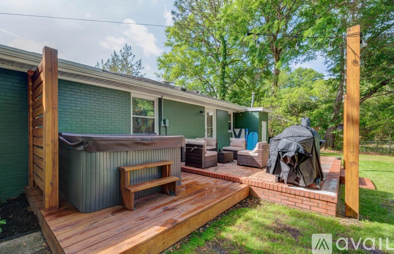A wooden deck with a hot tub and a grill on a sunny day.
