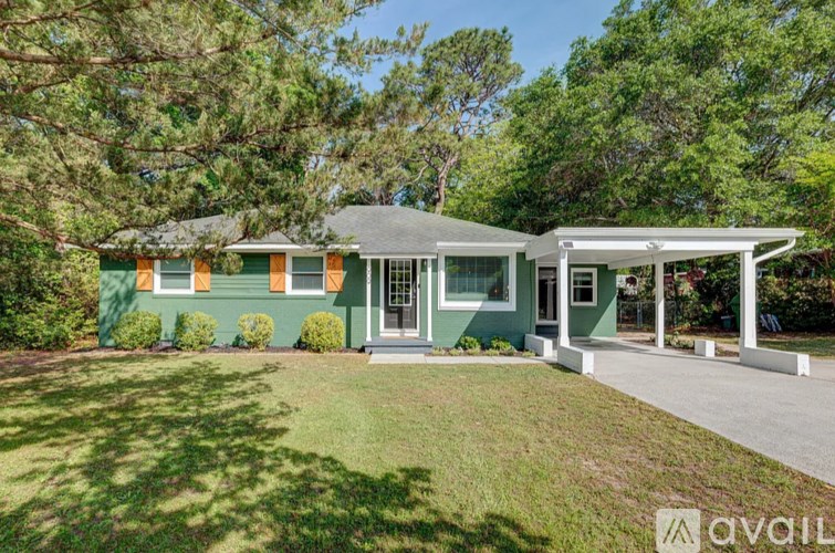 A green house with a white garage door is for sale.