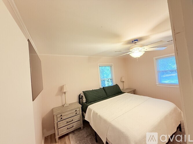 A bedroom with a bed, nightstand, and window.