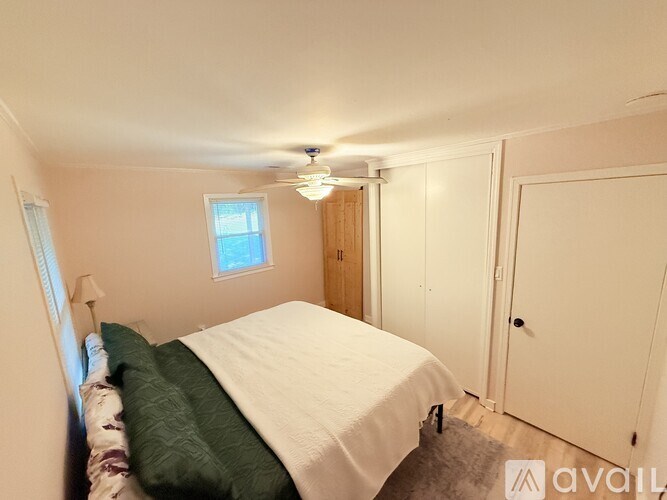 A bedroom with a bed, a window, and a ceiling fan.