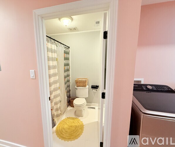 A bathroom with a toilet, a shower curtain, and a yellow rug.