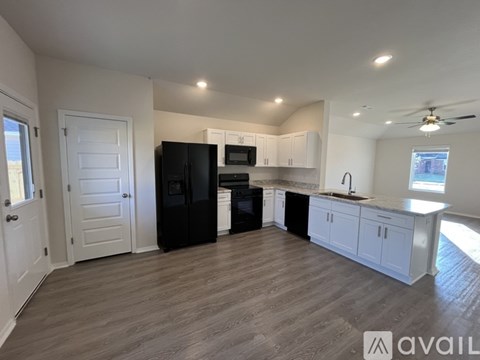 A kitchen with black appliances and white cabinets.