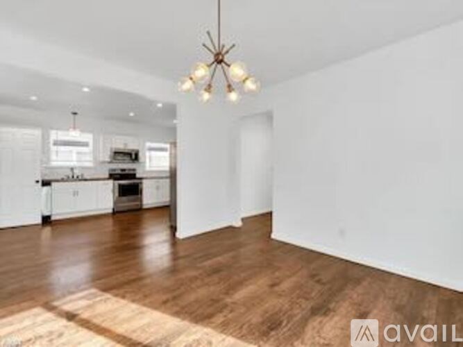 A spacious room with wooden floors and a chandelier hanging from the ceiling.