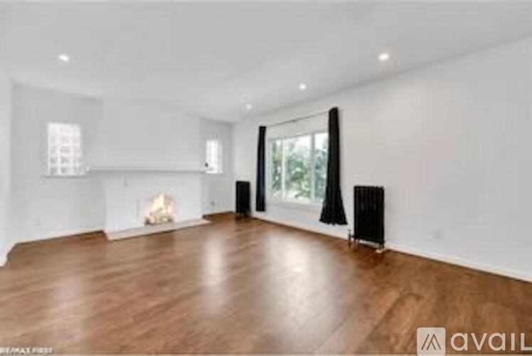 A spacious room with wooden flooring and white walls.