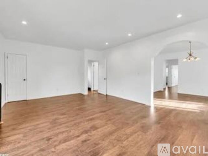 A spacious room with wooden flooring and white walls.