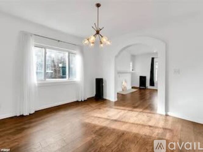A room with wooden floors and a chandelier hanging from the ceiling.