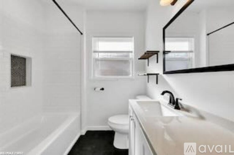 A white bathroom with a toilet, sink, and mirror.