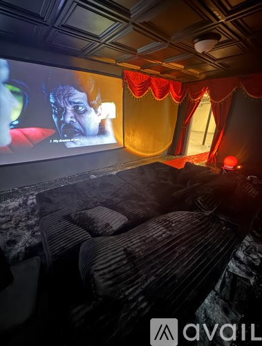 A movie theater with a screen showing a movie and a red light on.