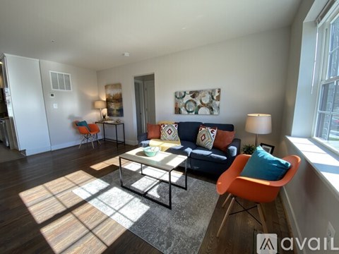 A living room with a blue couch and a glass coffee table.