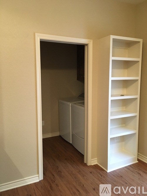A white shelving unit with a refrigerator in the corner of a room.