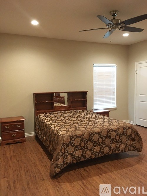 A bedroom with a bed, dresser, and ceiling fan.