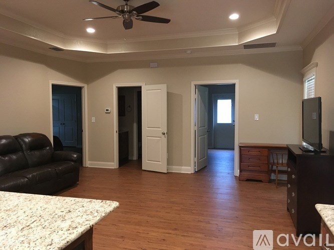 A living room with a black leather couch and a ceiling fan.