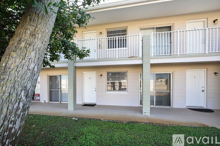 A building with a balcony and a tree in front of it.