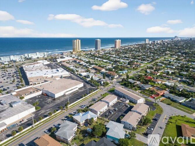 A bird's eye view of a city with buildings, roads, and a beach in the distance.