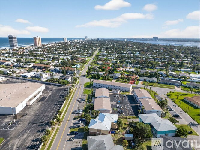 A large industrial building is in the foreground of a city with a beach in the background.