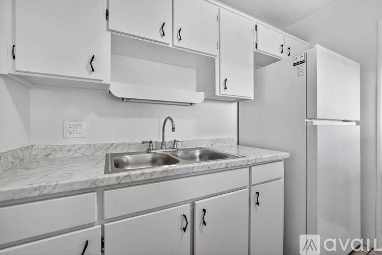 A kitchen with white cabinets and a marble countertop.