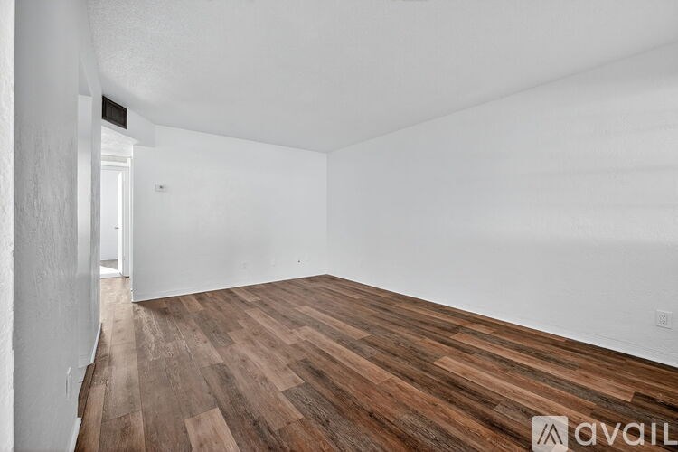 A room with wooden flooring and white walls.
