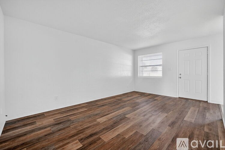 A room with wooden flooring and white walls.