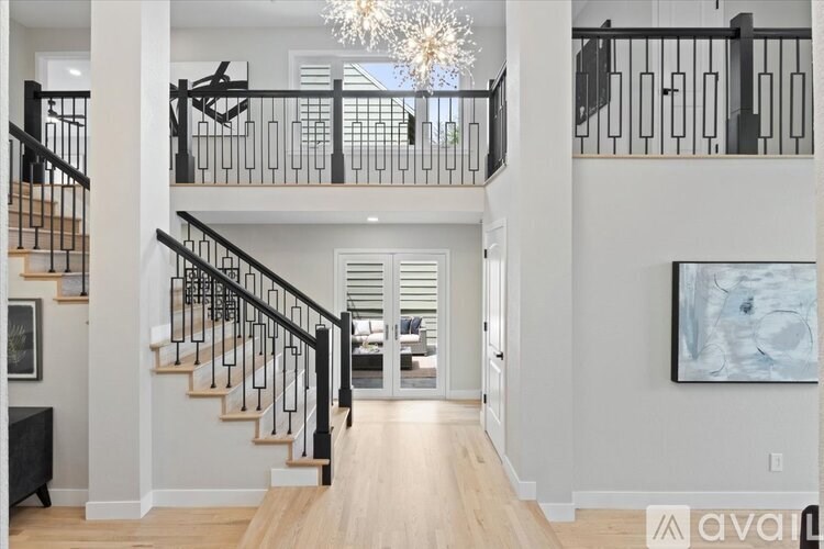 A modern interior of a house with a staircase and a chandelier.