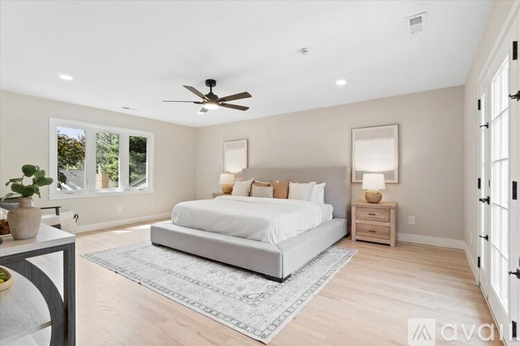 A bedroom with a large bed, a ceiling fan, and a rug on the floor.