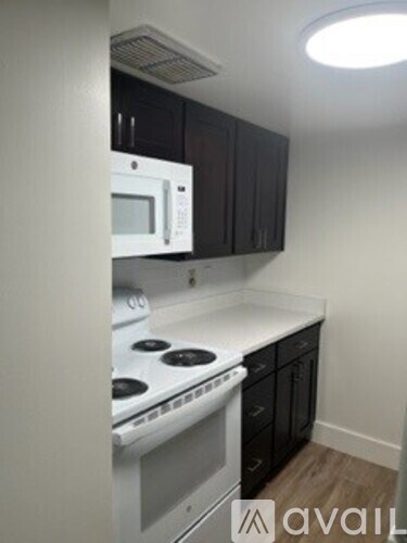 A kitchen with a white stove top oven and black cabinets.
