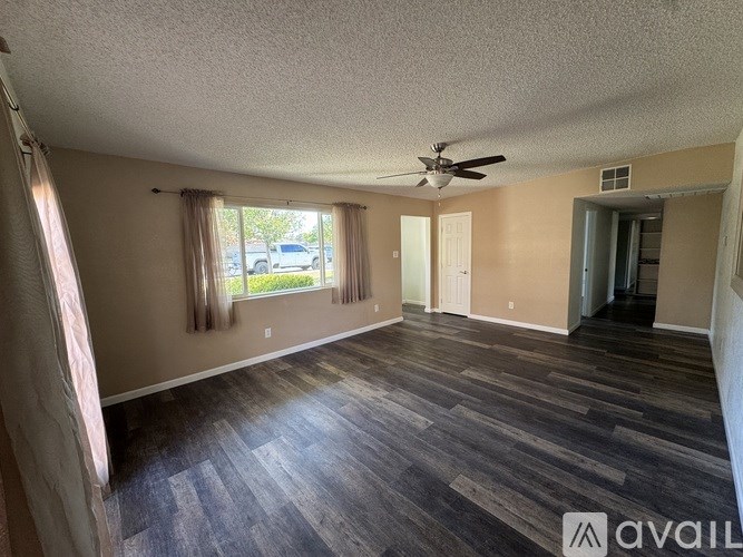 A room with a ceiling fan and wooden flooring.