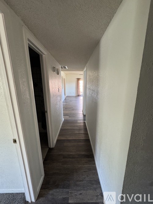 A long hallway with a door on the left and a window on the right.