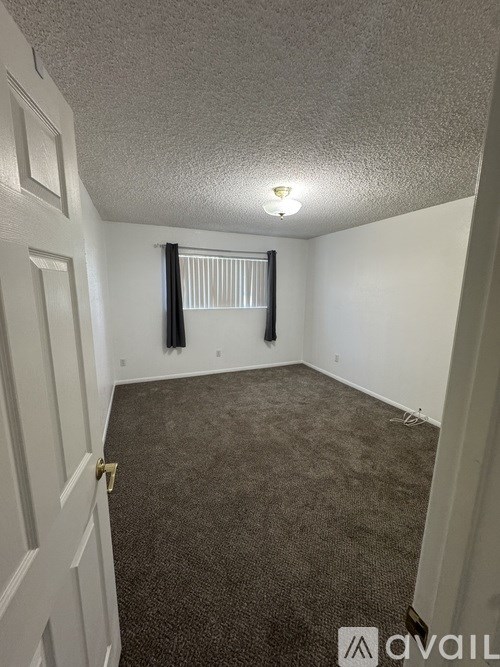 A room with a carpeted floor and a window with blinds.