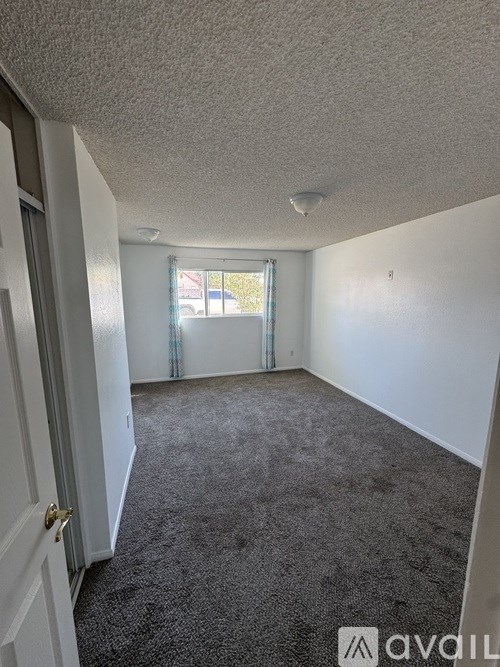 A room with a carpeted floor and a door on the left.