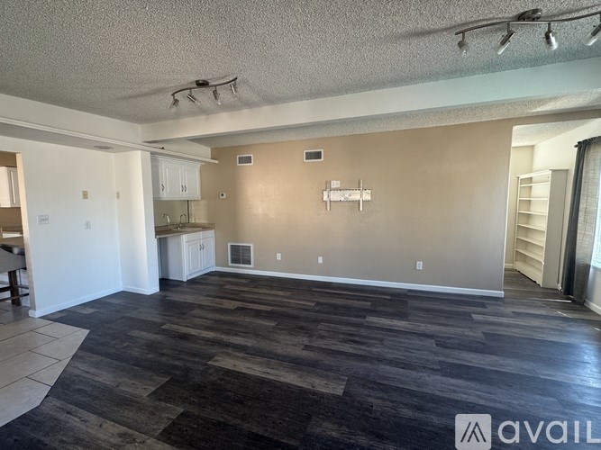 A spacious room with a kitchen area and a dining table.