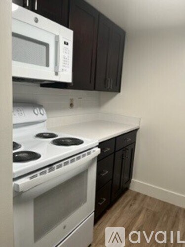 A white microwave oven is mounted above a white stove in a kitchen.