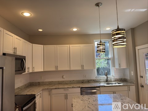 A kitchen with white cabinets and a granite countertop.