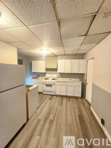 A kitchen with white cabinets and a wooden floor.